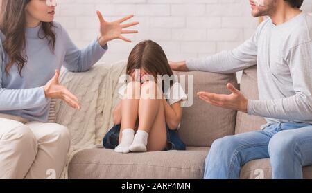 Petite fille innocente assise entre les parents disputant et pleurer Banque D'Images
