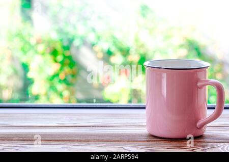 Une tasse de thé rose se tient sur un bas de caisse en bois sur le fond d'un jardin d'été Banque D'Images