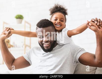 Beau père noir et petite fille imitant des avions Banque D'Images