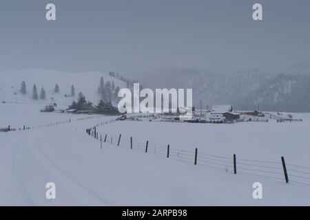 Une journée froide d'hiver. Une grange en bois et des bâtiments de ferme en bois dans la neige, sur une ferme à cheval éloignée dans les John long Mountains, au-dessus de Beavertail, Montana. Être Banque D'Images
