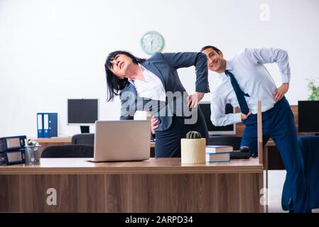 Les deux employés qui font des exercices de sport au bureau Banque D'Images