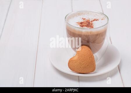 Tasse de café et bisquit doux en forme de coeur sur la table blanche Banque D'Images