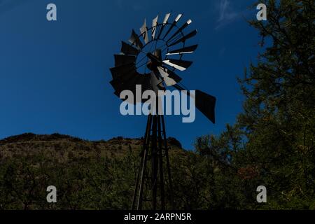 Un moulin à vent pompe de l'eau souterraine sur une ferme de Karoo près de la ville de Cradock, au Cap oriental, en Afrique du Sud, pendant la sécheresse prolongée de l'intérieur Banque D'Images