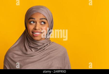 Femme noire douteuse musulmane dans le foulard qui pit la lèvre et regarde de côté Banque D'Images