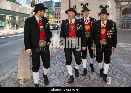 Hommes portant des vêtements tyroliens traditionnels, devant l'église jésuite (Jesuitenkirche), l'église universitaire d'Innsbruck, Tyrol, Autriche Banque D'Images