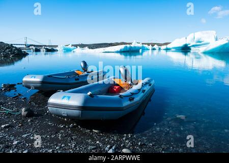 De petits bateaux gonflables motorisés à moteur se trouvent sur le bord de la lagune de glace à Jökulsárlón, en Islande Banque D'Images