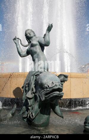 une fille qui monte une statue de dauphin Banque D'Images