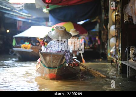 Bangkok/ Thaïlande - 29 décembre 2019: Le vendeur local vend le produit sur le fleuve dans le marché flottant de Damnoen Saduak. Le marché flottant est un des points de vue Banque D'Images