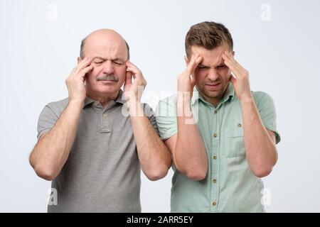 Expressions et émotions négatives du visage humain. Les hommes mécontents gardent les doigts sur les temples, les visages frown dans le mécontentement, souffrent de maux de tête. Studio s Banque D'Images
