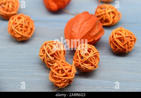 Physalis orange vif et boules en osier sur fond bleu en bois. Banque D'Images