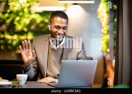 Homme d'affaires noir souriant faisant des appels vidéo à la famille Banque D'Images