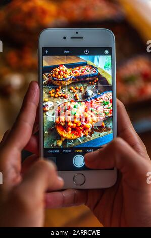Femme prenant la photo d'un courge musquée rôtie avec un iPhone Banque D'Images