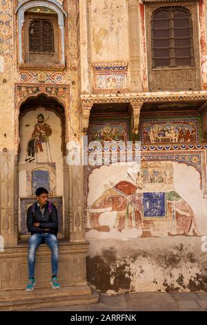 Inde, Rajasthan, Shekhawati, Nawalgarh, Nayabazaar, homme assis à l'extérieur de Haveli en mauvais état Banque D'Images