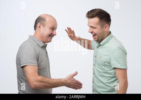 Deux hommes caucasiens matures, le père et le fils, se serrent les mains pour conclure un accord. Studio tourné Banque D'Images