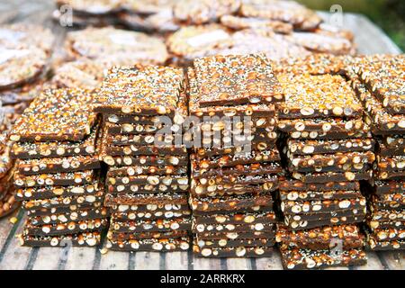 Une pile de barres cassantes d'arachide couvertes de graines de sésame pour la vente sur une table de bambou sur un marché aux Visayas, Philippines Banque D'Images