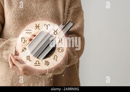 Femme avec livres d'astrologie sur fond clair Banque D'Images