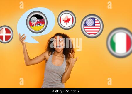 Une femme afro-américaine tenant une bulle de discours avec UNE ÉCOLE de LANGUE de texte et des drapeaux de différents pays sur fond jaune Banque D'Images