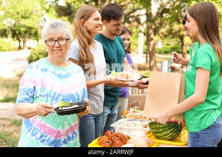 Les jeunes bénévoles en donnant de la nourriture aux pauvres à l'extérieur Banque D'Images