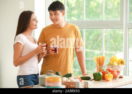 Heureux couple boire du jus pendant la cuisson dans la cuisine Banque D'Images