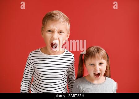 Portrait de petits enfants en colère sur fond couleur Banque D'Images