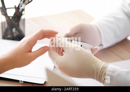 Médecin vérifiant le taux de sucre dans le sang de la femme diabétique en clinique, closeup Banque D'Images