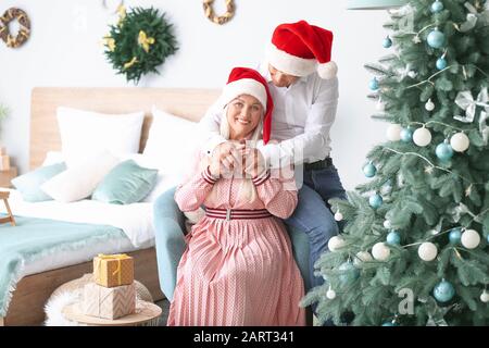 Heureux couple d'âge mûr célébrant Noël à la maison Banque D'Images