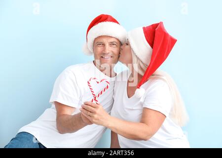 Joyeux couple d'âge mûr avec des bonbons de Noël sur fond clair Banque D'Images