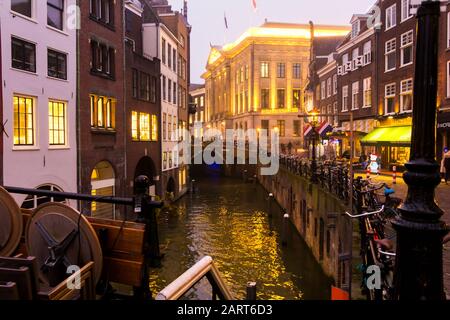 Utrecht, Pays-Bas, 21 Janvier 2020. Un pont en pierre à l'arc traversant le canal, dans le centre d'Utrecht. Soirée Misty, vue nocturne sur le canal, maisons anciennes Banque D'Images