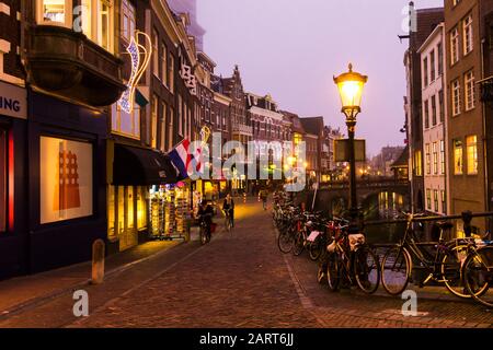 Utrecht, Pays-Bas, 21 Janvier 2020. Pont en pierre à double arc traversant le canal, dans le centre d'Utrecht. Soirée Misty, vue de nuit sur le canal, maisons Banque D'Images