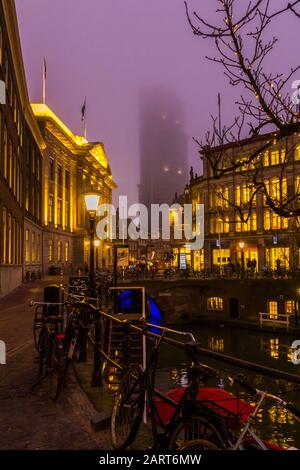 Utrecht, Pays-Bas, 21 Janvier 2020. Un pont en pierre à l'arc traversant le canal, dans le centre d'Utrecht. Soirée Misty, vue nocturne sur le canal, Dom Tower Banque D'Images