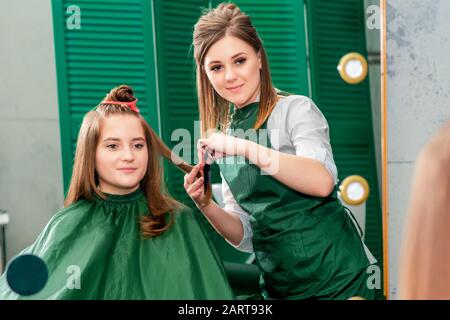 Coiffeur et client regardant dans le miroir pendant la coiffure au salon de beauté. Banque D'Images