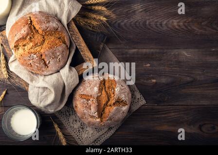 Pain de seigle fait maison avec des graines de coriandre et un verre de lait sur fond rustique en bois. Vue de dessus. Espace pour le texte. Banque D'Images