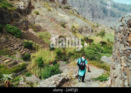 Saint Antao Cap-Vert. Randonneur avec sac à dos qui descend dans la vallée. Terrain rocheux de hautes chaînes de montagne et de profondes ravines autour. Banque D'Images