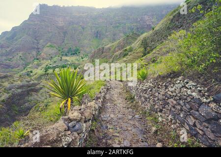 Saint Antao Cap-Vert. Sentier pédestre pavé menant à la vallée. Terrain rocheux de hautes chaînes de montagne et de grands ravins en arrière-plan. Banque D'Images