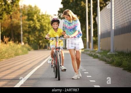 Mère enseignant à son fils de faire du vélo à l'extérieur Banque D'Images