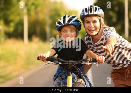 Mère enseignant à son fils de faire du vélo à l'extérieur Banque D'Images