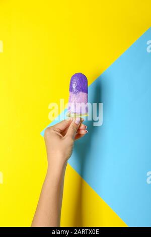 Main féminine avec une délicieuse glace aux bleuets sur fond de couleur Banque D'Images