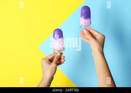 Mains féminines avec une délicieuse glace aux bleuets sur fond de couleur Banque D'Images