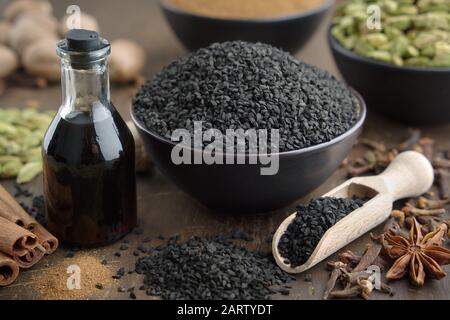 Graines de cumin noir ou de coriandre romaine et bouteilles d'huile de caraway noir, épices aromatiques sur table: Cardamome, anis, clous de girofle, cannelle, curcuma. Ingrédient Banque D'Images