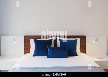 Chambre moderne avec murs blancs et oreillers décoratifs de couleur bleue Banque D'Images