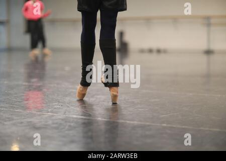Jambes d'une ballerine debout sur pointe dans des chaussettes chaudes à une répétition dans le hall Banque D'Images