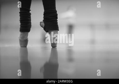 Jambes d'une ballerine debout sur pointe dans des chaussettes chaudes à une répétition dans le hall Banque D'Images