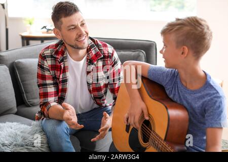 L'enseignement du père son petit-fils à jouer de la guitare à la maison Banque D'Images