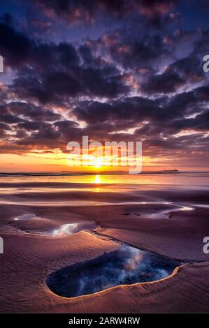 Lever du soleil sur la plage de Bamburgh surplombant les îles Farne, Bamburgh, Northumberland, angleterre, Royaume-Uni Banque D'Images