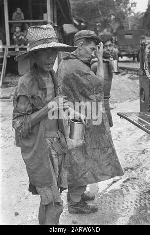 Photo Retarage Palembangs Fortement skinneyed l'homme indonésien. Au milieu du soldat néerlandais, homme avec enfant et regard. Jeeps Date : Janvier 1947 Lieu : Indonésie, Antilles Orientales Néerlandaises, Palembangs, Sumatra Banque D'Images