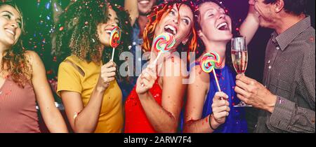 Joyeux amis célébrant la veille de la nouvelle année en buvant du champagne à la discothèque - les jeunes s'amusent à danser avec des sucettes au club de discothèque Banque D'Images