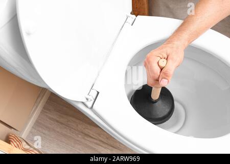 L'homme à l'aide d'un piston pour déboucher les toilettes Photo Stock -  Alamy