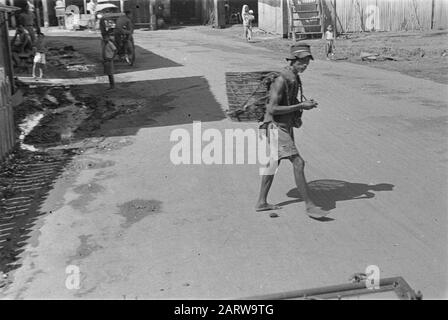 Photo Reportage Palembangs Streetscape Palembangs. Homme indonésien avec panier sur son dos Date: Janvier 1947 lieu: Indonésie, Antilles orientales néerlandaises, Palembangs, Sumatra Banque D'Images