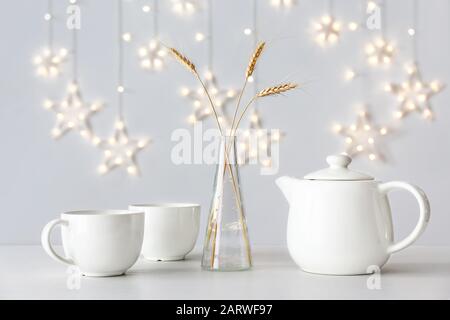 Théière avec tasses et vase avec spiquets de blé sur table Banque D'Images