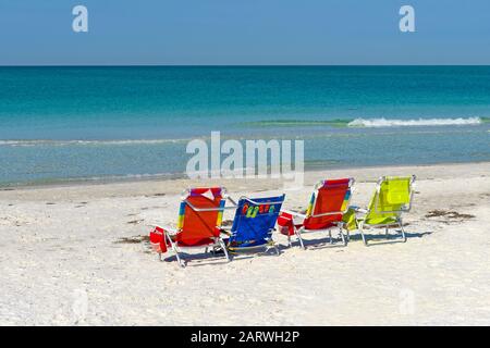 Quatre Chaises De Plage De Couleurs Vives Vides Sur La Plage Banque D'Images